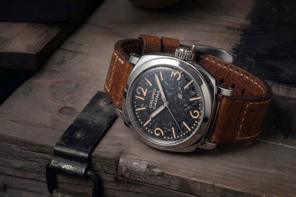 A wristwatch with a blue dial and brown leather strap resting on a rustic wooden surface.