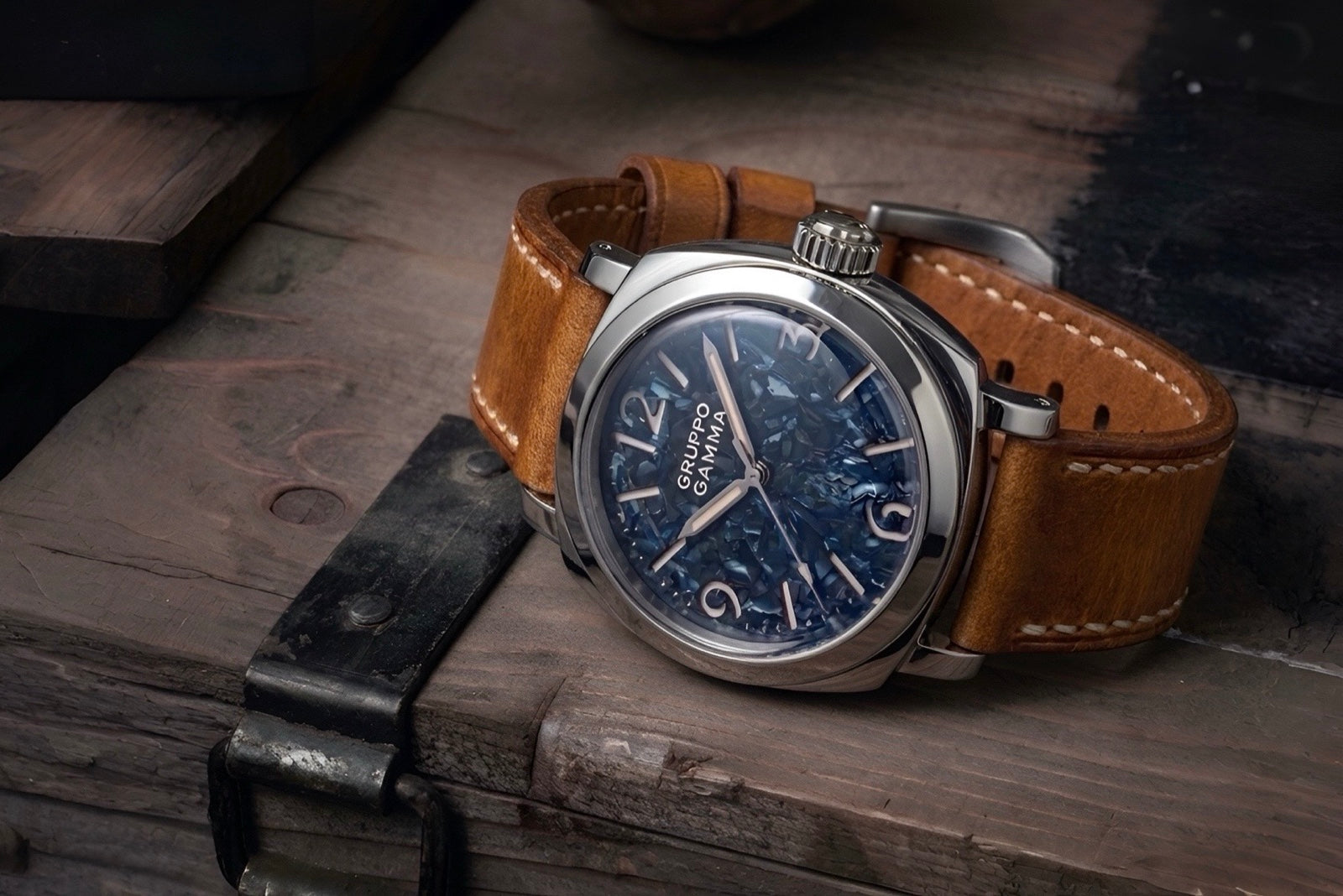 A wristwatch with a blue dial and brown leather strap resting on a rustic wooden surface.