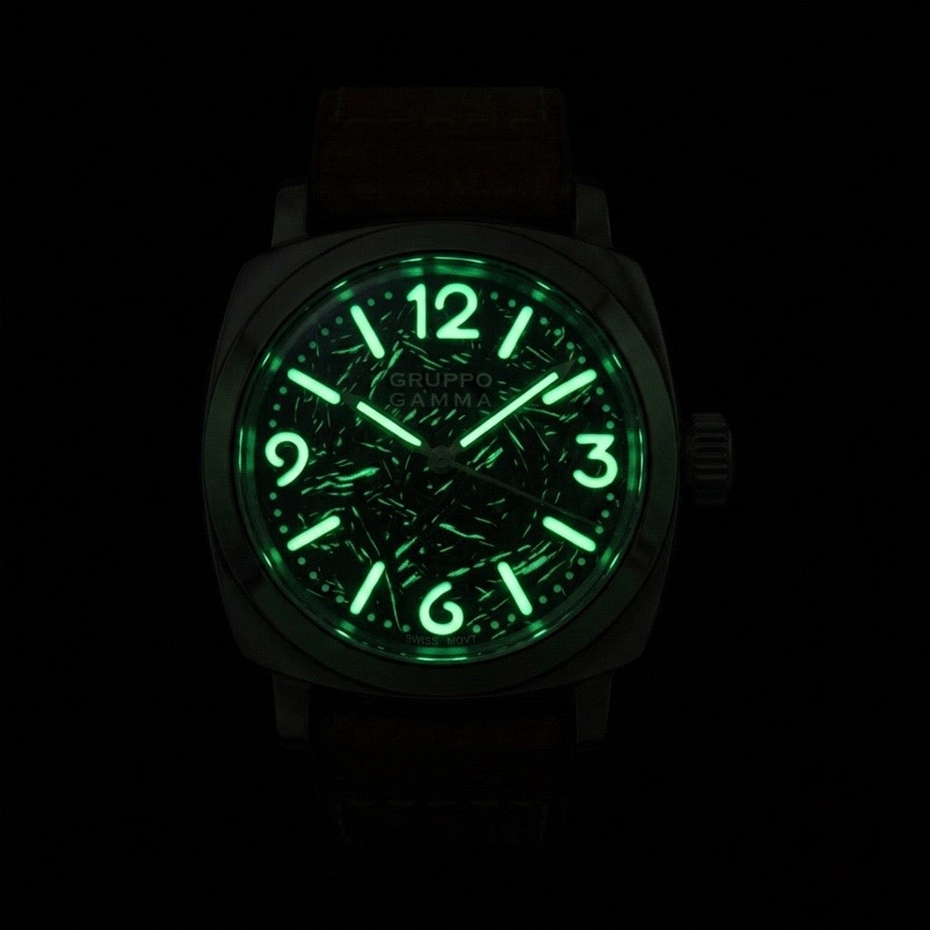 A Gruppo Gamma wristwatch with a glowing green luminescent dial, shown against a completely black background.