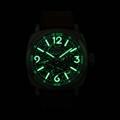 A Gruppo Gamma wristwatch with a glowing green luminescent dial, shown against a completely black background.