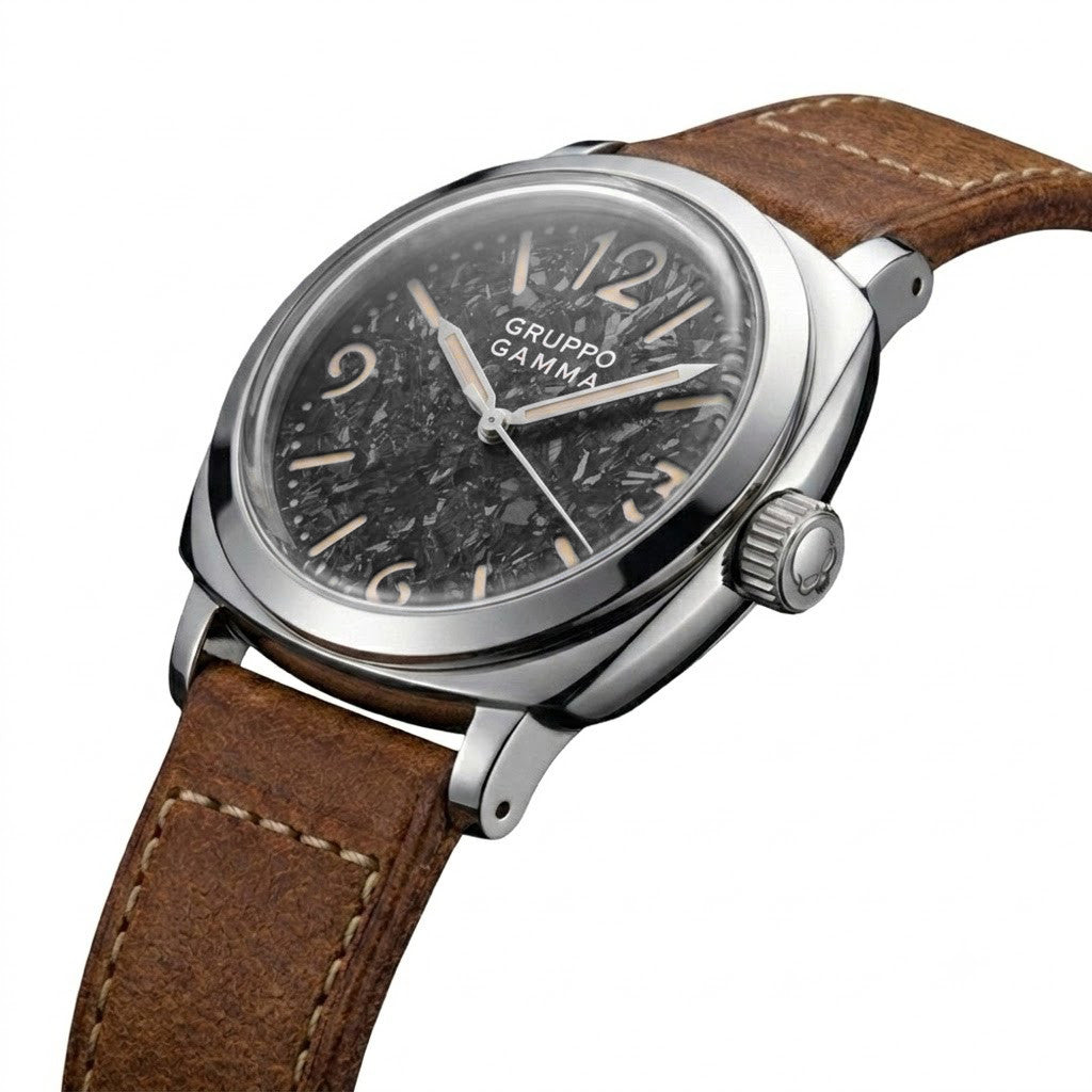 A Gruppo Gamma wristwatch featuring a black crystallized titanium dial, a polished stainless steel case, and a brown leather strap with white contrast stitching, shown on a clean white background.