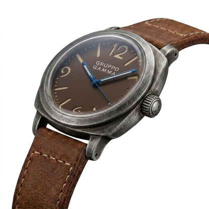 A vintage-style Gruppo Gamma wristwatch with an aged and distressed gray stainless steel case, tropical brown dial, blue steel hands and brown leather strap.
