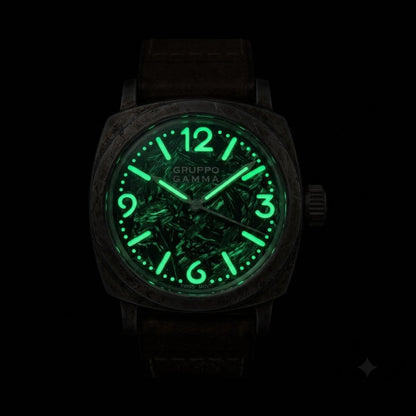 A Gruppo Gamma wristwatch with an aged steel case, a glowing green luminescent forged carbon dial, and a dark brown strap.