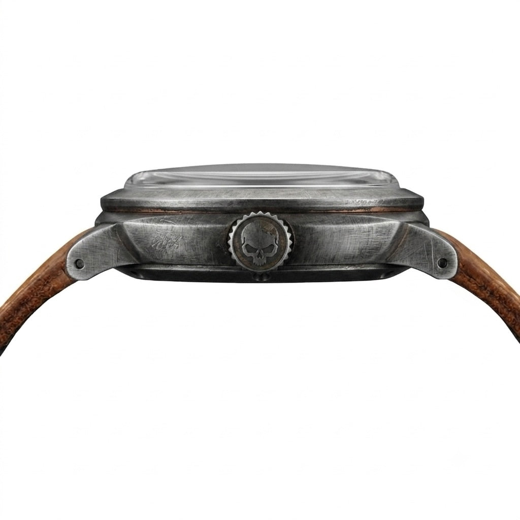 Close-up of a Gruppo Gamma watch case, showing an aged and weathered stainless steel finish, with a brown leather strap.