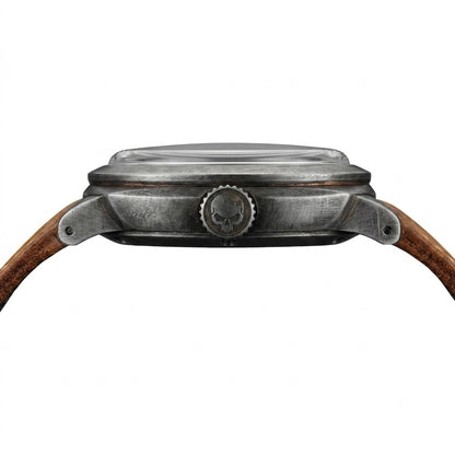 Close-up of a Gruppo Gamma watch case, showing an aged and weathered stainless steel finish, with a brown leather strap.