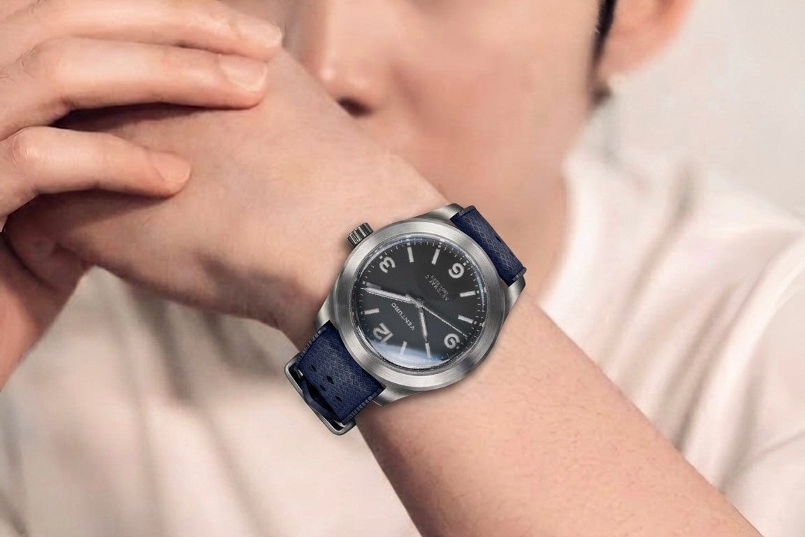Person wearing a watch with a blue strap on a blurred background