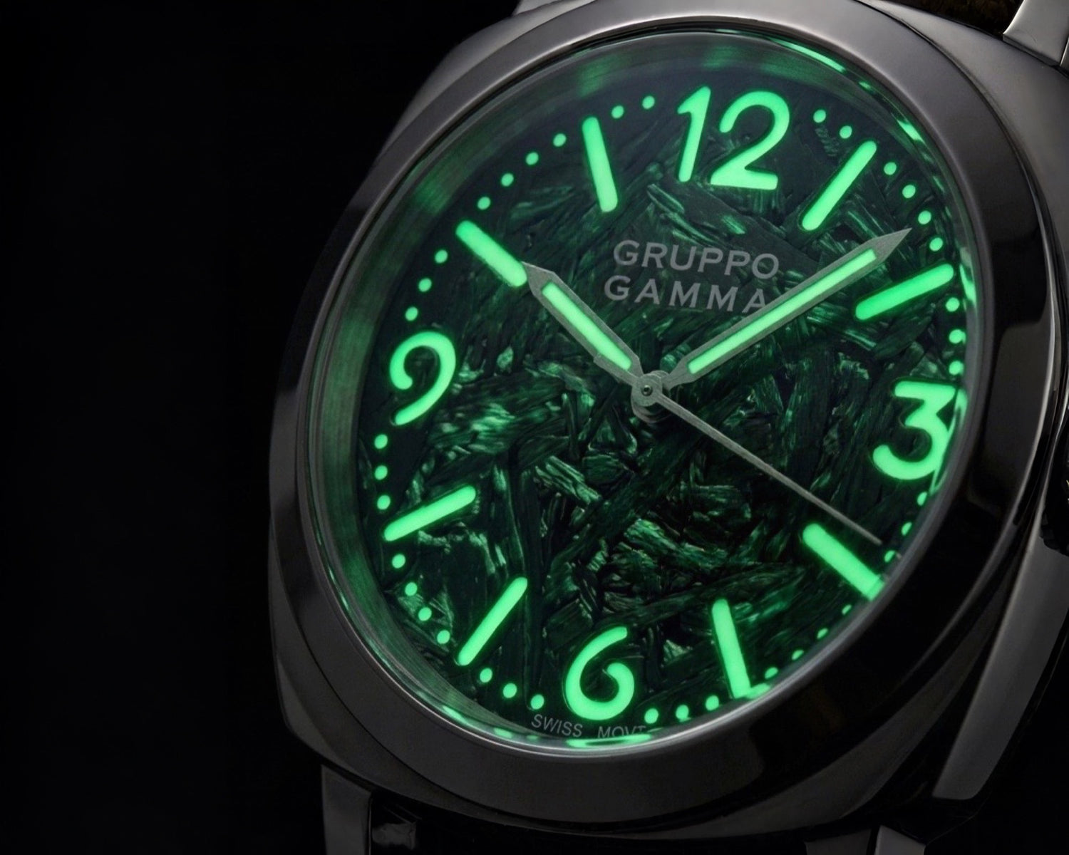 Close-up of a Gruppo Gamma wristwatch with a green luminescent forged carbon dial, glowing green numerals and hands.